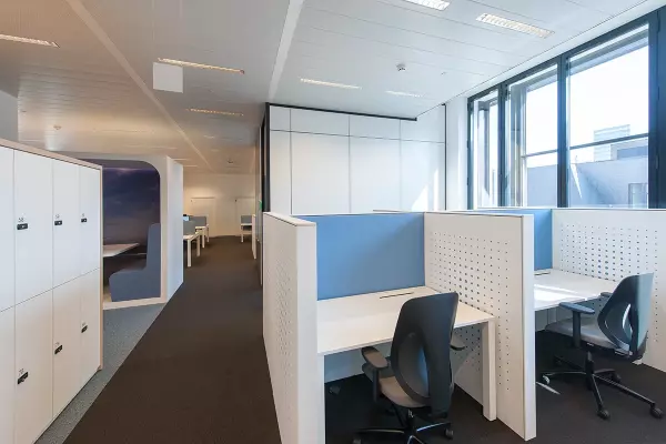 Individuele bureaus met ergonomische bureaustoel en lichtblauwe akoestische scheidingswand