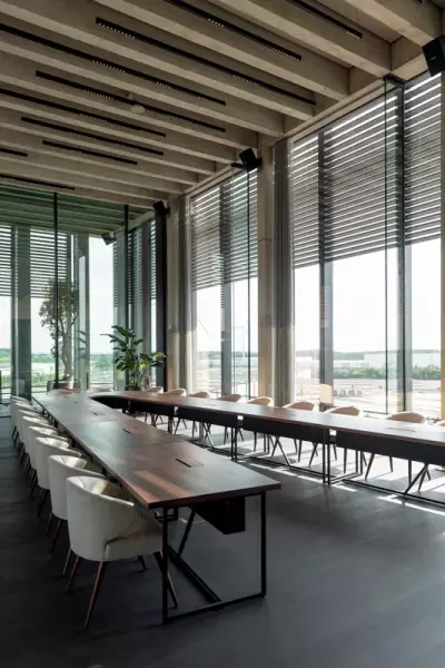 Grote houten vergadertafel in v-vorm met moderne vergaderstoelen
